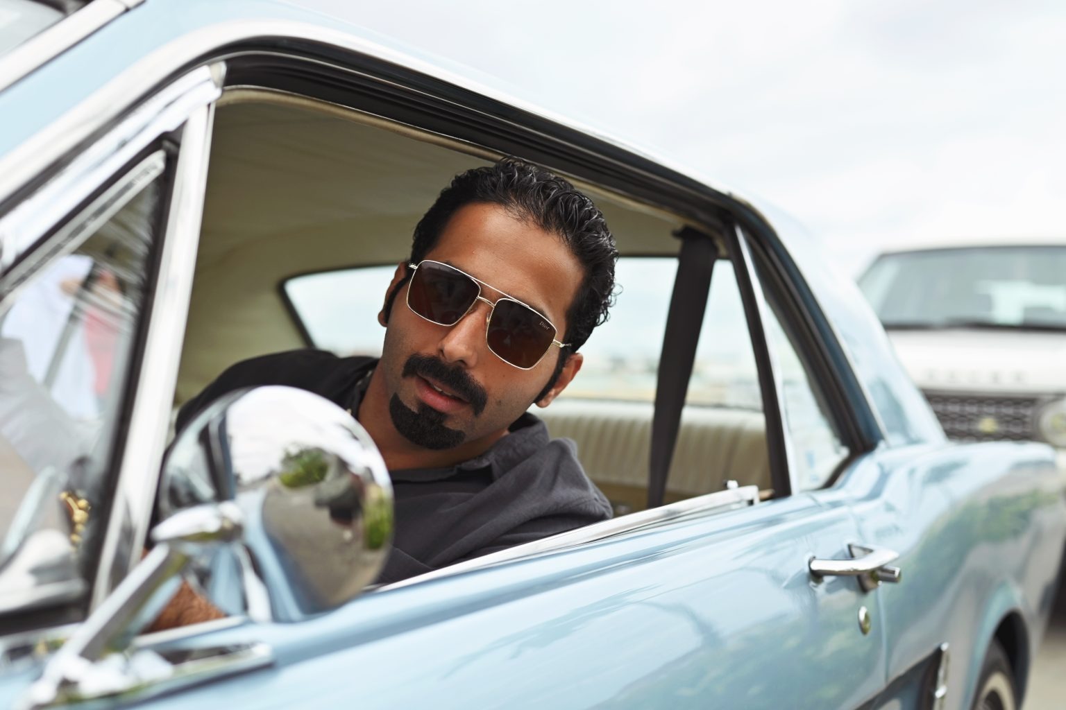 Fahad Al-Qahtani seated in a light-blue classic car for Esquire Arabia